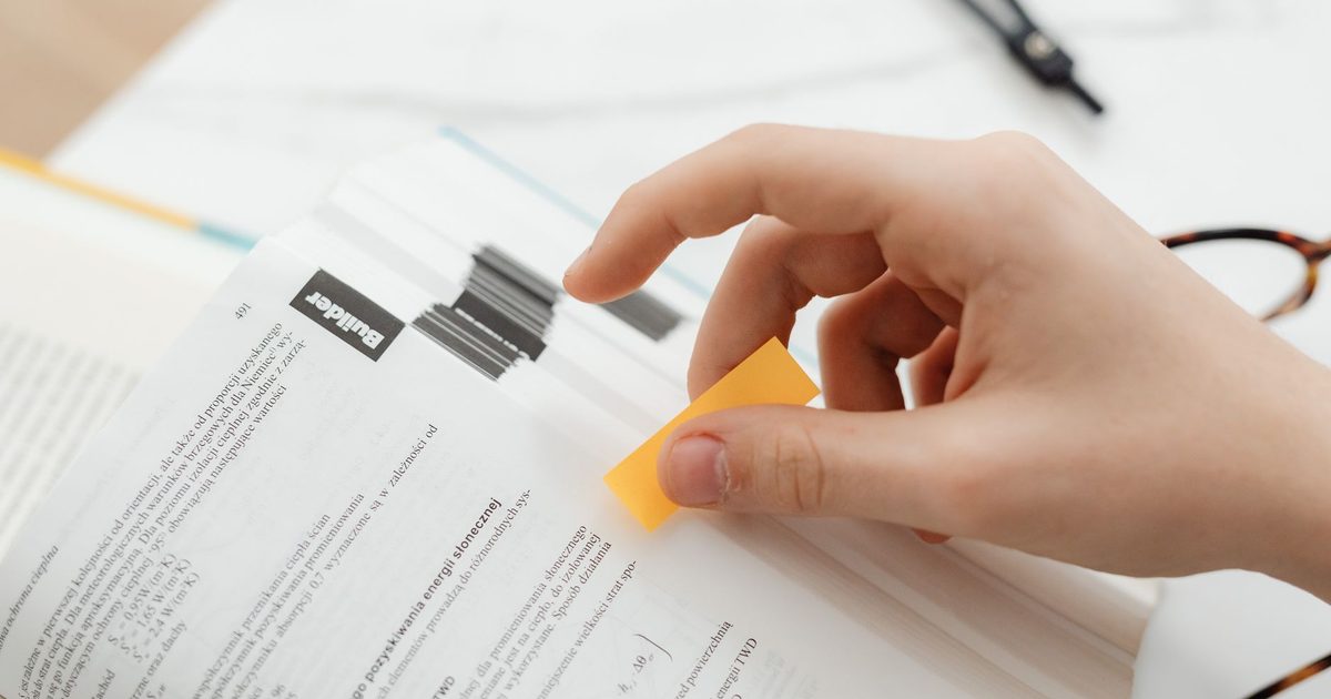 Mano che applica una linguetta adesiva su una pagina stampata già segnata