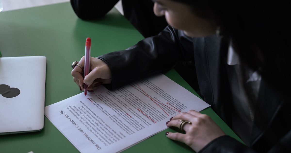 Persona che corregge un documento stampato con una penna rossa